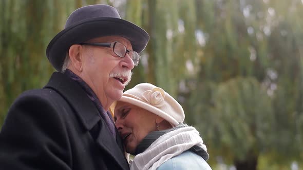 Old European man and woman dancing together in park standing.