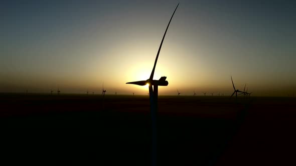 Sunset Over the Wind Turbines on a Wind Farm in the Quiet Summer Night, Silhouette, Aerial Survey