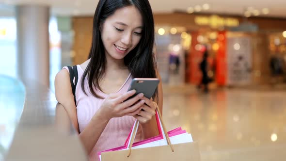 Woman using cellphone and holding shopping bags 