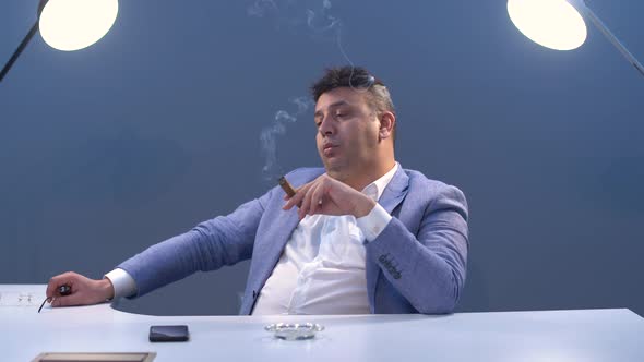 Businessman smoking cigar in his office.