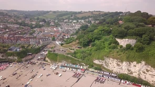 Aerial shot flying away from the Devon coastline with beautiful cliffs and buildings on the coast