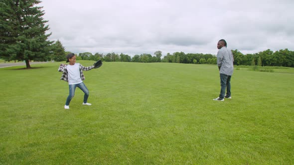 Positive African American Father and Son Training Baseball in Park