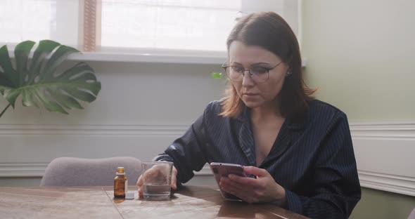 Excited Sad Mature Woman Reading Smartphone, Female Drinking Water with Medicine