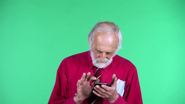 Portrait of Happy Old Aged Man 70s Communicates with Someone Texting on His Phone, Isolated Over