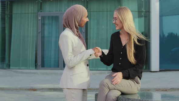 Friendly Smiling Millennial Colleagues Indian Girl in Hijab and Young European Woman Greeting Each