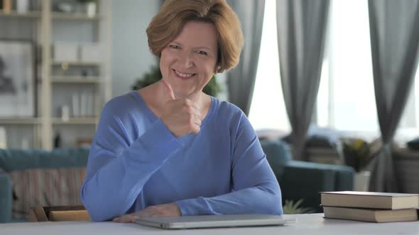 Thumbs Up By Old Senior Woman at Work Looking at Camera