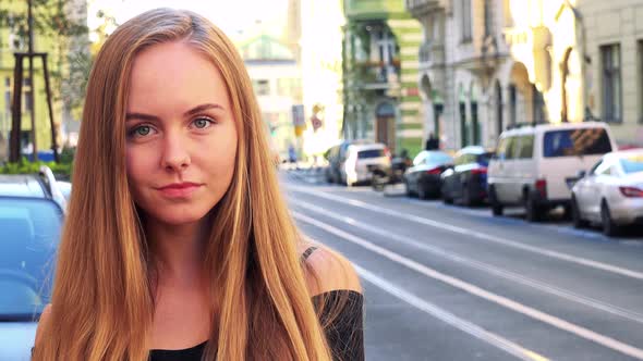 Young Beautiful Woman Smiles To Camera in the City - Street in the Background