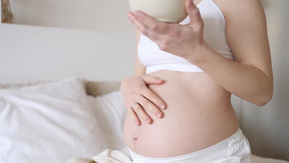 Pregnant Woman Touching Her Belly While Having Breakfast In Bed