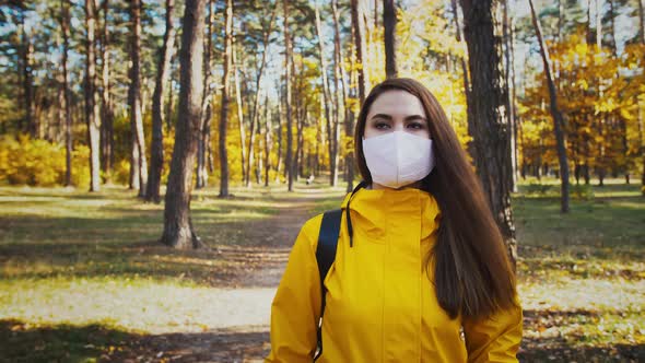 Young Woman Walking By Autumn Forest Stopping Taking Off Her Protective Mask Smiling and Taking a