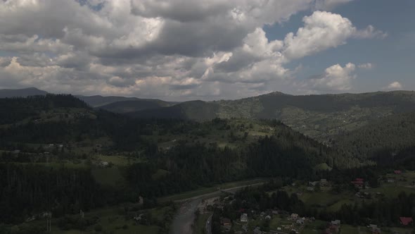 Flying over a river towards hills covered by forest in a landscape covered by small clusters of hous