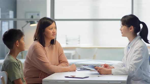 Asian Mother and Son Talking with Doctor in Clinic