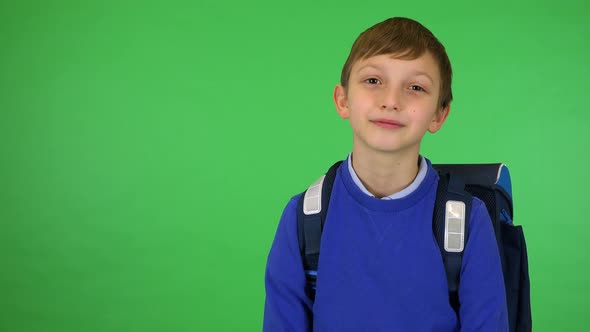 A Young Cute Boy with a Schoolbag Smiles at the Camera - Green Screen Studio