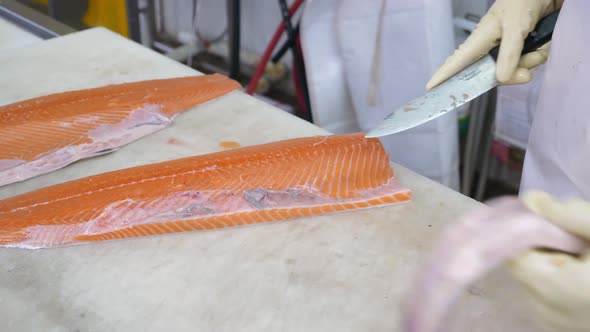 Closeup of Worker Hands Cutting and Cleaning Salmon Fillet Big Chopping Knife