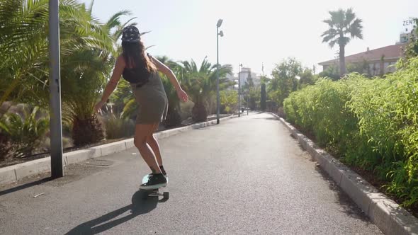 Beautiful Young Girl Rides on Road Near Beach and Palm Trees on Longboard in Slow Motion