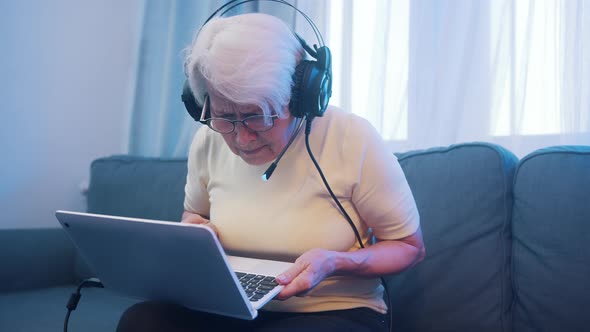 Elderly Woman with Headset Having Video Call with Family