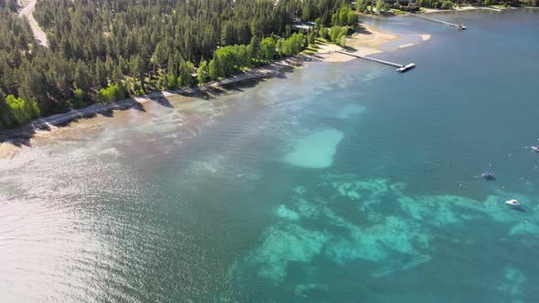 Drone fly's above North lake tahoe with boats anchored in shallow water towards a savemart in Tahoe