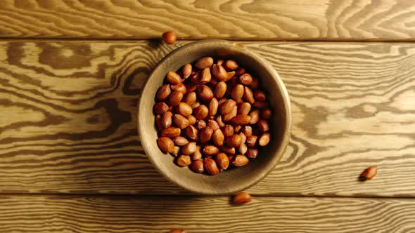 SLOW: Peeled Peanuts Fall Into A Wooden Dish On A Table - Top View