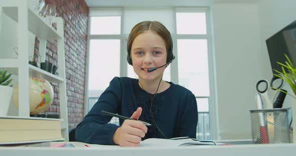 Child Girl Wearing Headphones Studying Online By Video Call with Remote Teacher Tutor