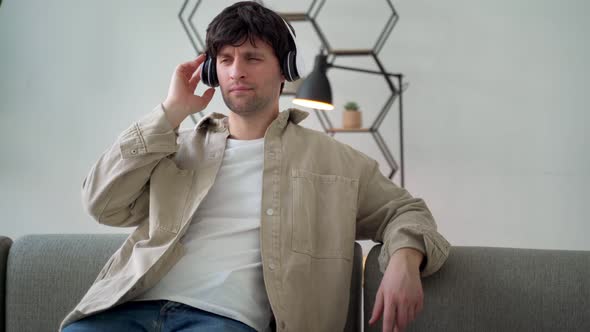 Relaxed Casual Man Sitting Down Listening to Music with Headphones