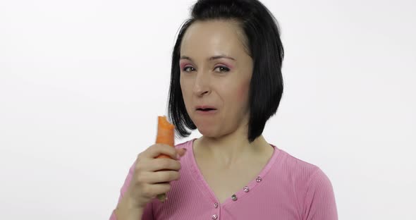 Young Beautiful Woman Eating Big Carrot on White Background and Giggle