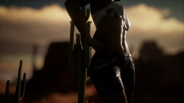 Woman in Torn Shirt Standing By Cactus in Desert at Sunset