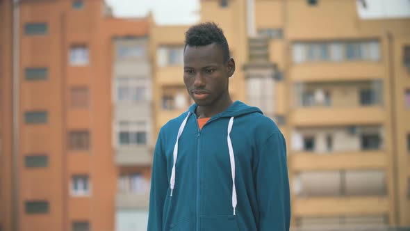 Confident Proud Black Young Man Looking at Camera-Buildings in Background