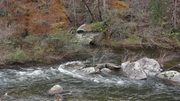 Drone shot of river flowing around rocks in late fall in western North Carolina.