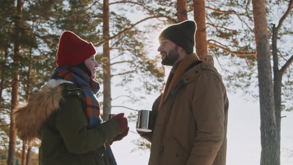 Couple Enjoying Hot Tea in Forest in Winter