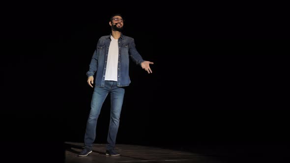 Young Male Business Coach Speaking Passionately From the Stage and Speaking Through a Microphone in