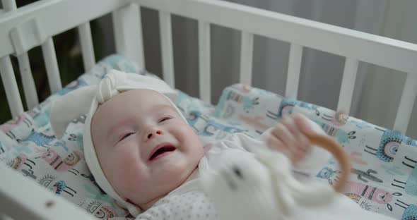 Portrait of a Cute Smiling Newborn Baby Lying in the Cradle Playing