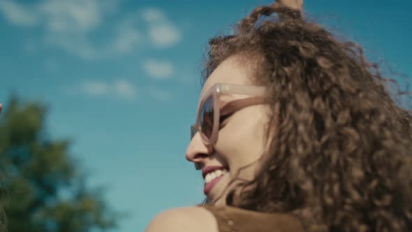 Camera tracking smiling young caucasian woman with curly hair dancing at music festival among friend