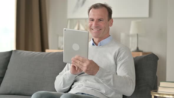 Middle Aged Businessman Doing Video Chat on Tablet at Home