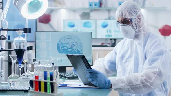 In Modern Laboratory Scientist in Coverall Is Working on a Digital Tablet PC alt