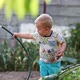 Little boy holds a hose in his hands, plays with water and watered the garden - VideoHive Item for Sale