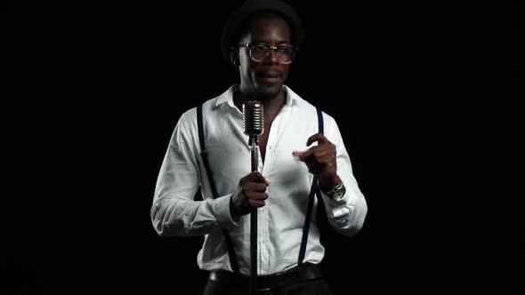 African American in a Studio Is Singing Songs Into a Microphone. Black Background. Slow Motion