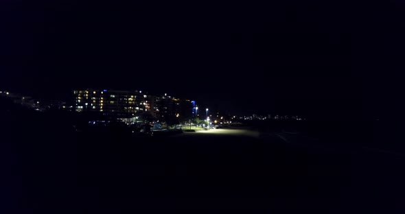 REALTIME shot of lightning flashes over the beach of a coastal town at night