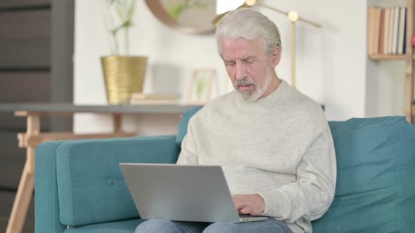 Old Man with Laptop Having Wrist Pain on Sofa