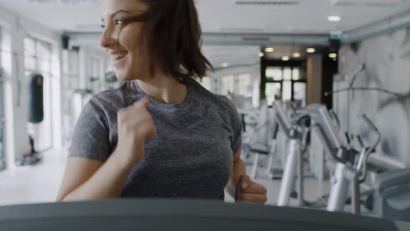 Handheld view of young women running on the treadmill at gym.  Shot with RED helium camera in 8K