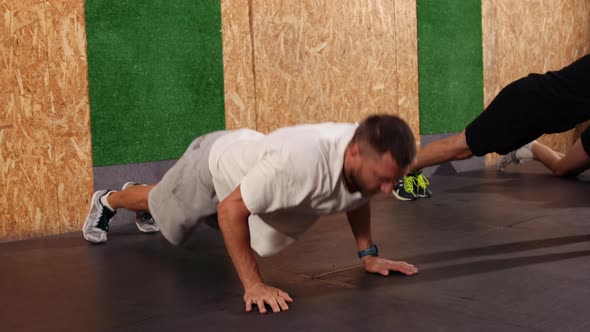 Strong Fit Athletic Men Doing Push Up Exercises in a Loft Style Industrial Gym