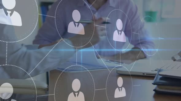 Businessmen signing documents and shaking hands with connected people icons in the foreground