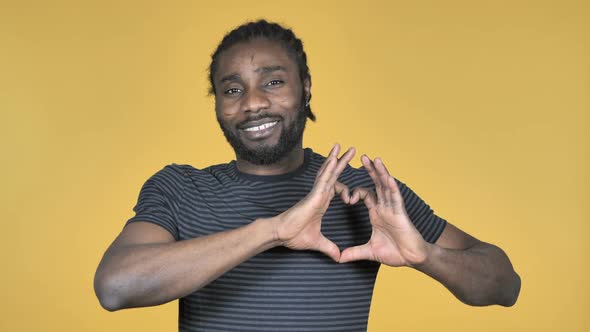 Handmade Heart By Casual African Man Isolated on Yellow Background