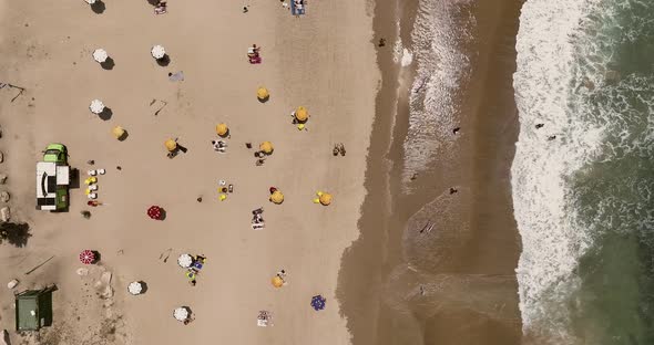 Crowded public beach with colourful umbrellas and people in the water and relaxing on the sand, Aeri