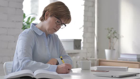 Pensive Old Woman Thinking and Writing Paperwork