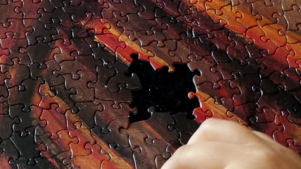 A hand works on a colorful puzzle.