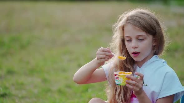 Cute little girl on meadow. Happy girl eating at meadow background