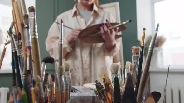 Smiling Woman Artist in the Studio  Paint Brushes on the Foreground