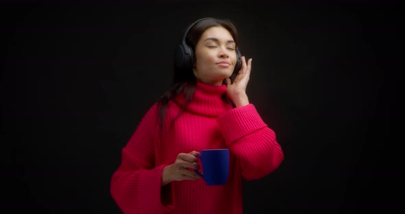 Beautiful Woman in a Bright Pink Sweater Enjoys Music in Wireless Headphones