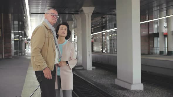 Senior Couple Waiting for a Train on the Station. Aged Travelers Waiting for Delayed Train