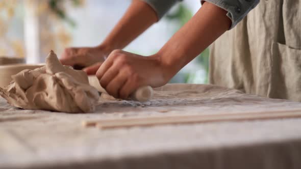 Female hands rolling out clay with a rolling pin