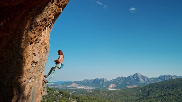 Side View of Strong Attractive Man Rock Climber Getting Ready to Descend From Vertical Cliff on Top